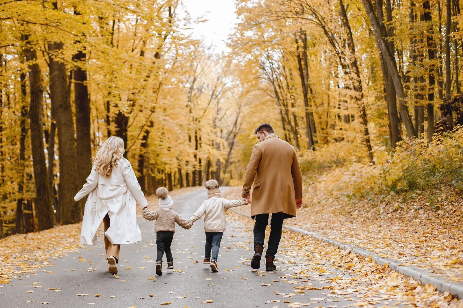 A family walking together along a tree lined autumn path