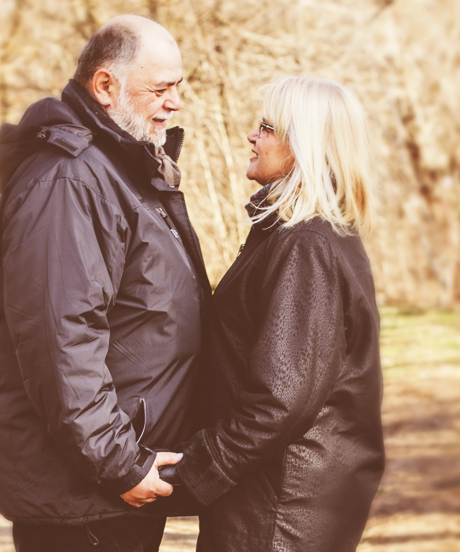 An older couple holding hands on a woodland path