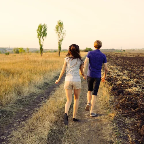 Couple walking in rural field at sunset 2026