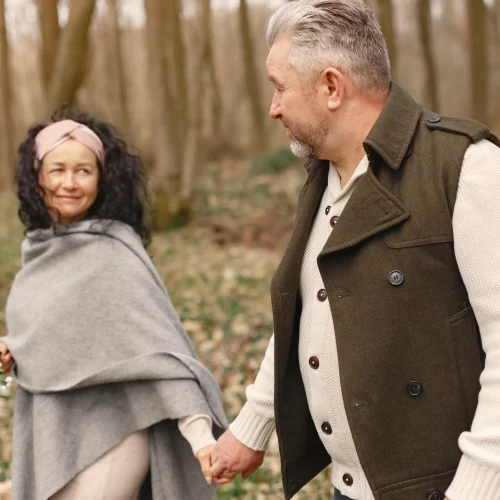 A couple walking hand in hand through a spring forest